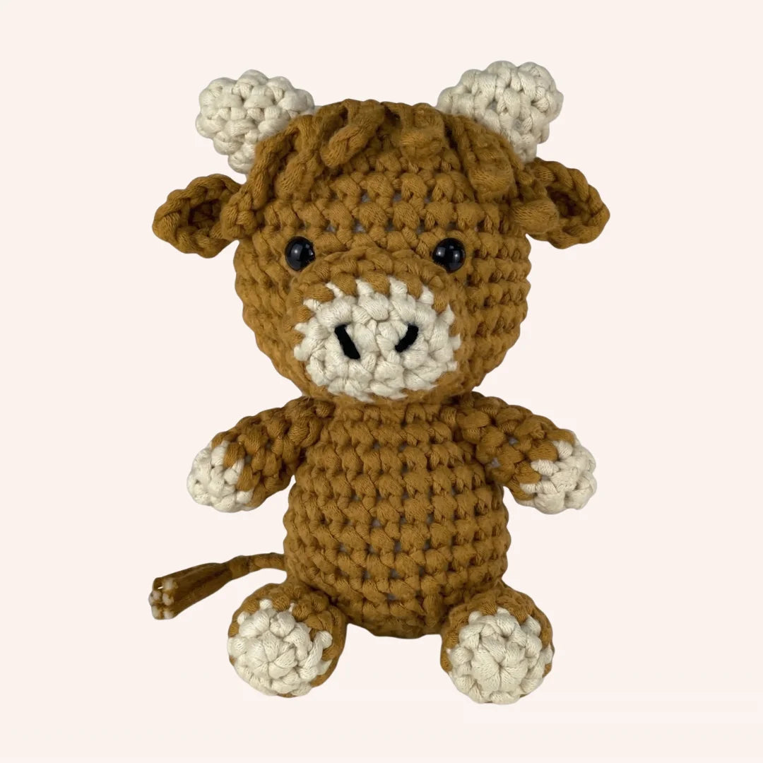 The Prairie Companion mini crochet buffalo amigurumi kit with brown and cream yarn on beige background