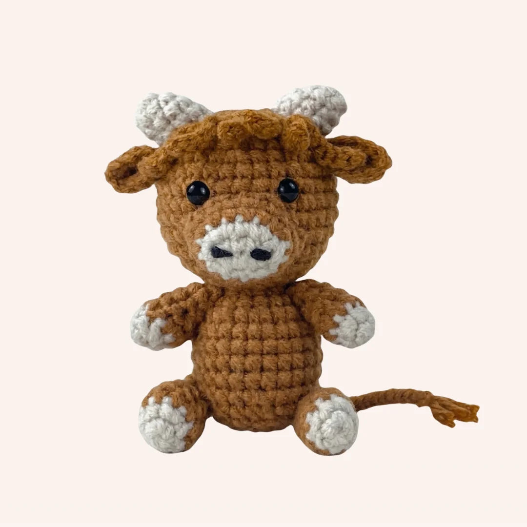 The Gentle Moo mini crochet amigurumi cow with brown body, white accents, horns and tail