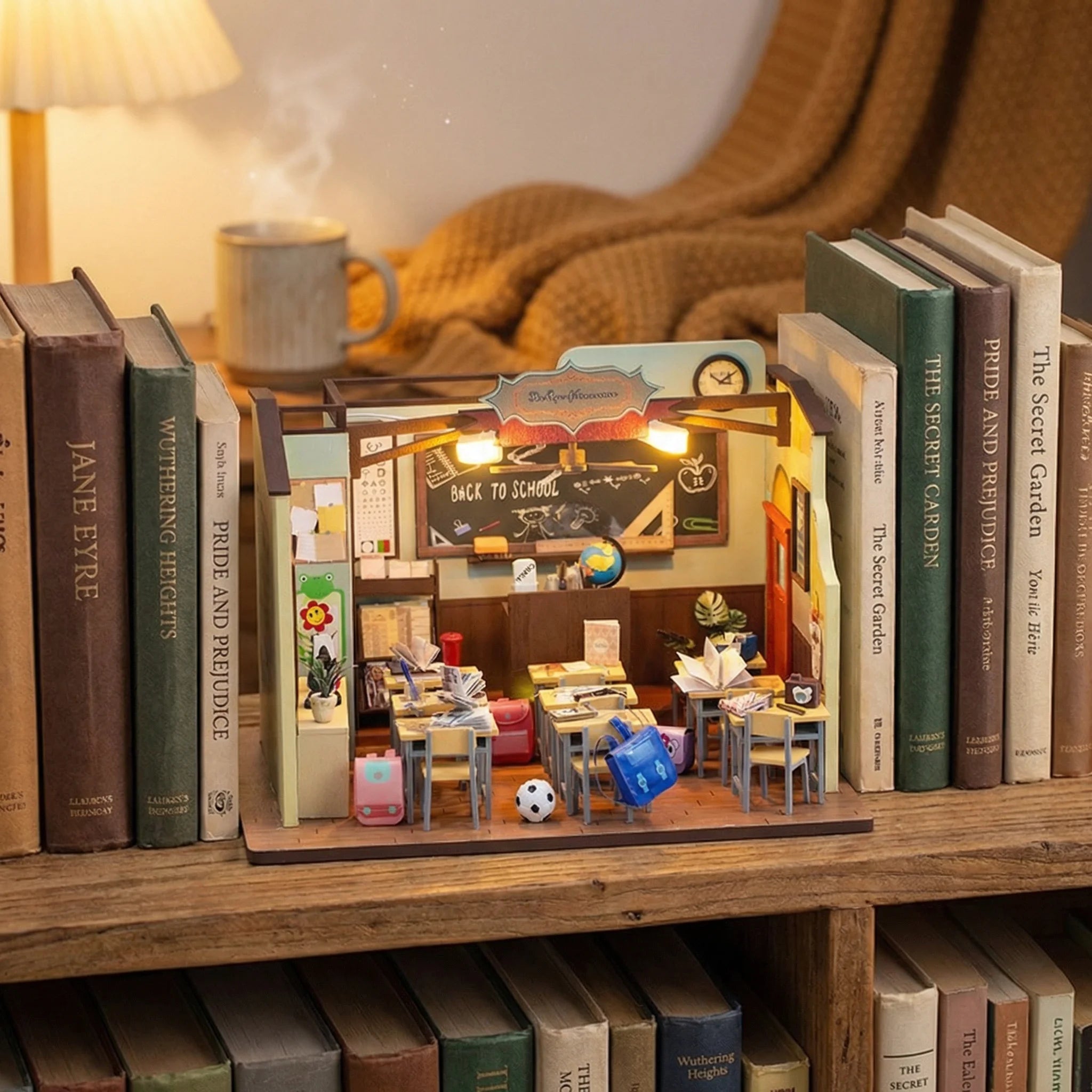 The Homeroom miniature DIY kit displayed on bookshelf with warm lighting showing detailed classroom scene with desks and d...