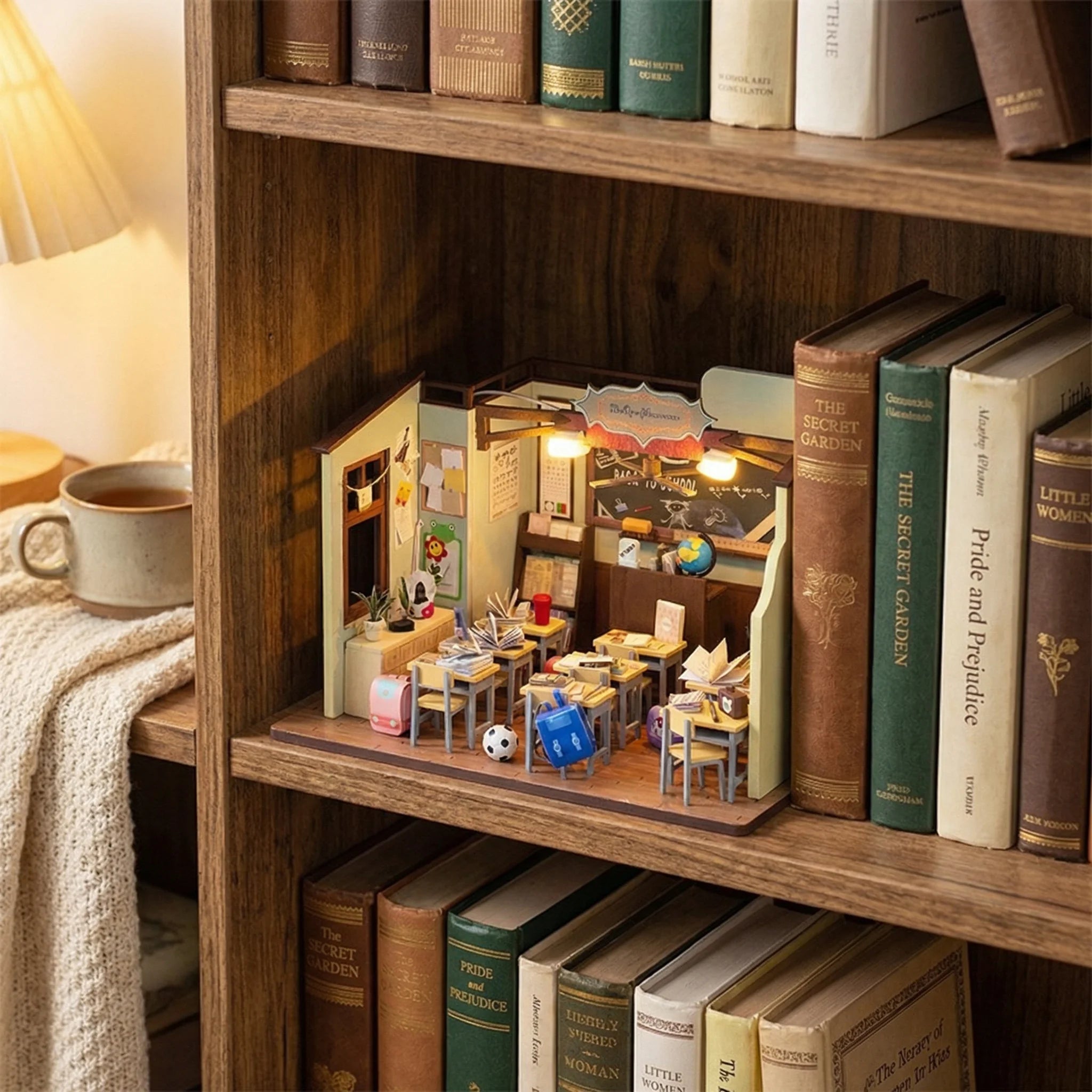 The Homeroom miniature DIY classroom kit displayed on bookshelf between books with detailed furniture and decor