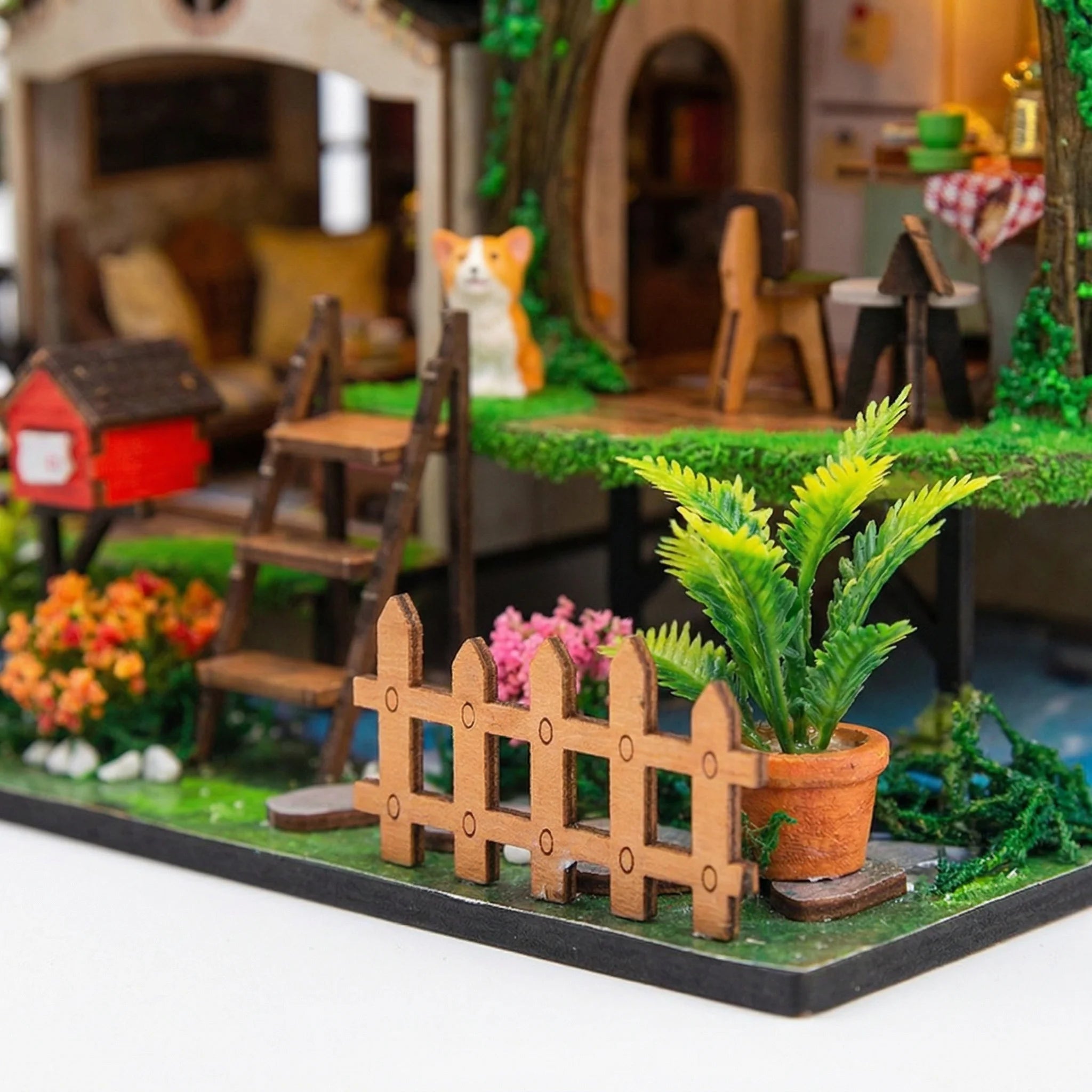 Garden Hideaway DIY miniature kit close-up showing wooden fence, potted fern, flowers and orange cat detail