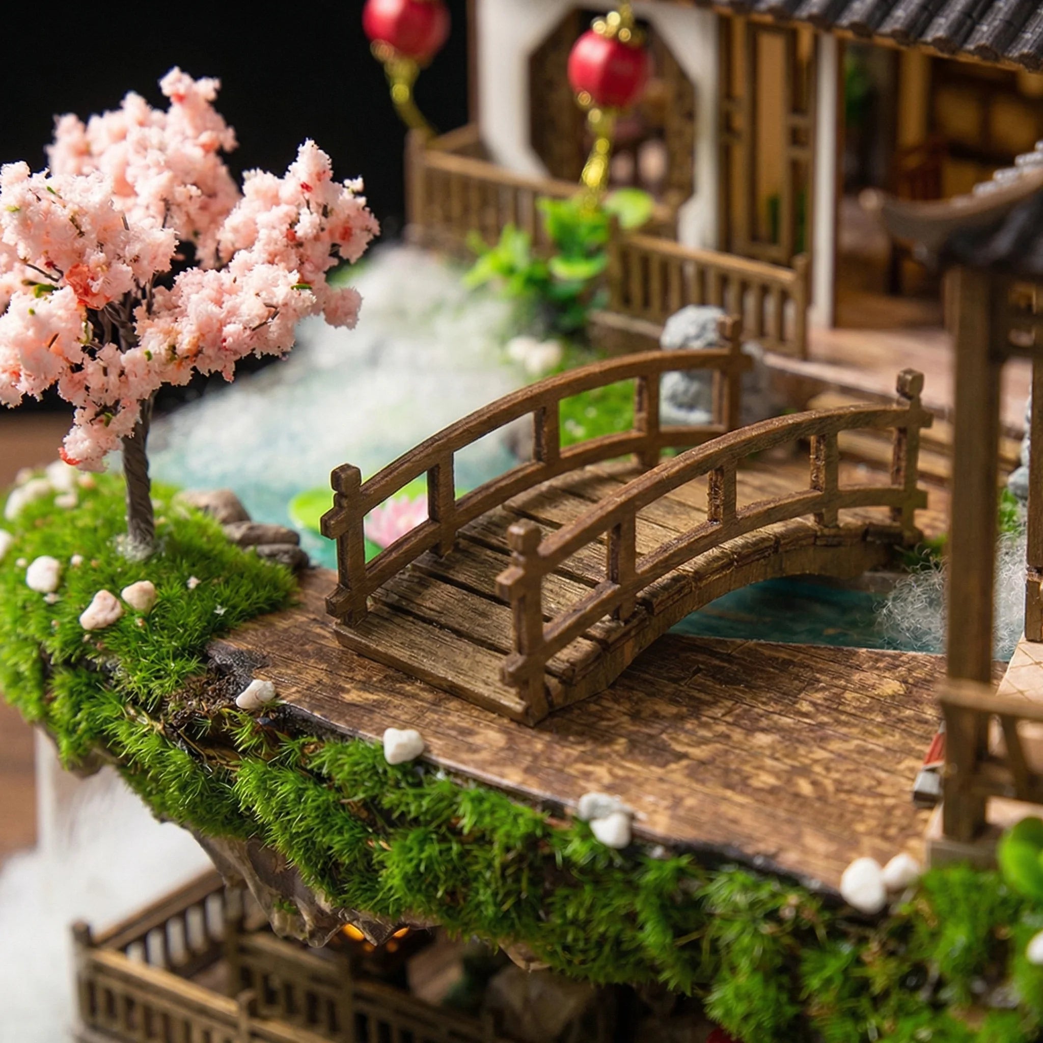 The Lotus Pavilion miniature kit featuring detailed wooden bridge over water with cherry blossom tree and traditional buil...