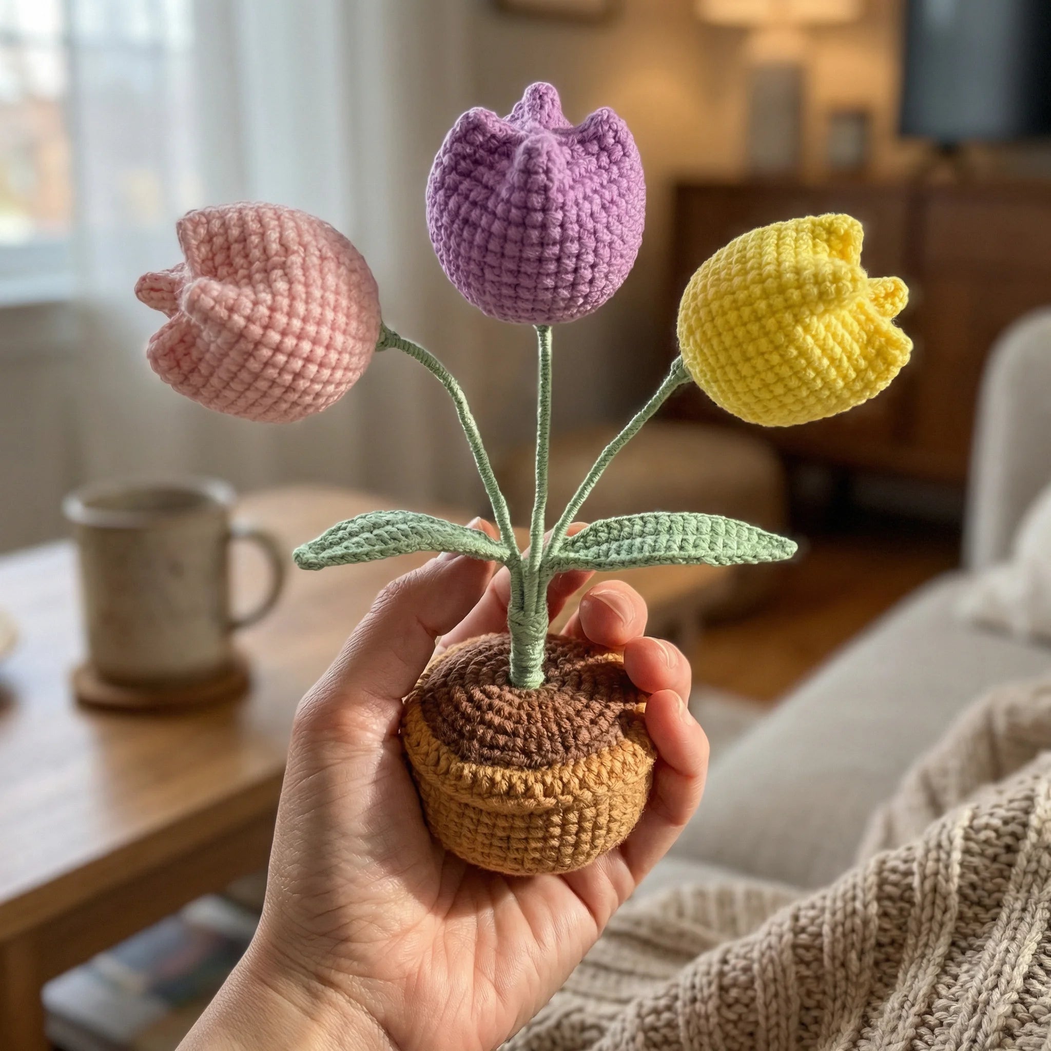 Hand holding The Tulip Garden mini crochet kit with three colorful amigurumi tulips in yellow pot