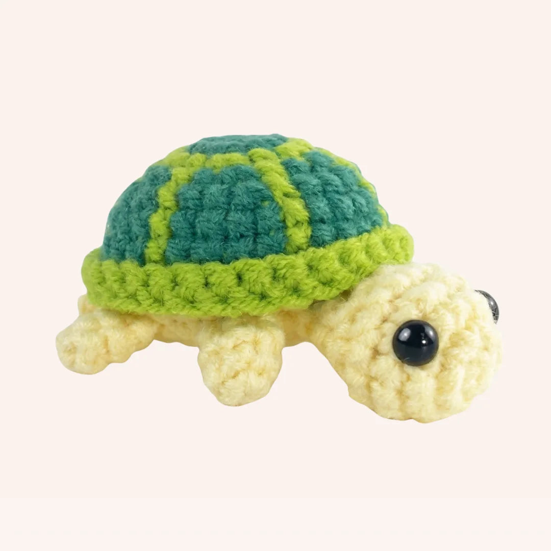 The Meadow Traveler mini crochet turtle amigurumi with teal and lime green striped shell and cream body