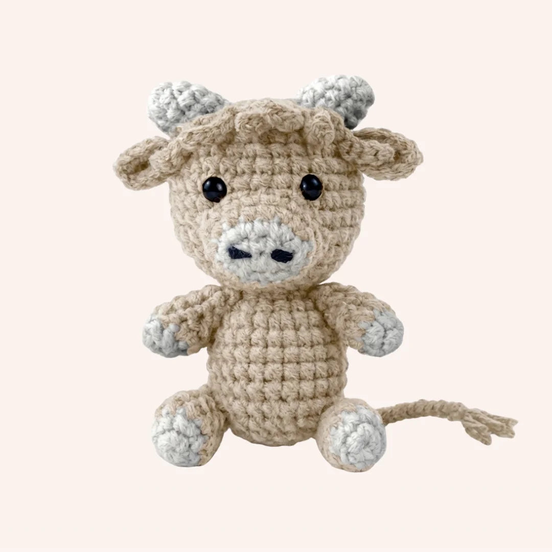 Buttercup the Cow mini crochet amigurumi plush with beige body, gray hooves and horns, and embroidered face details