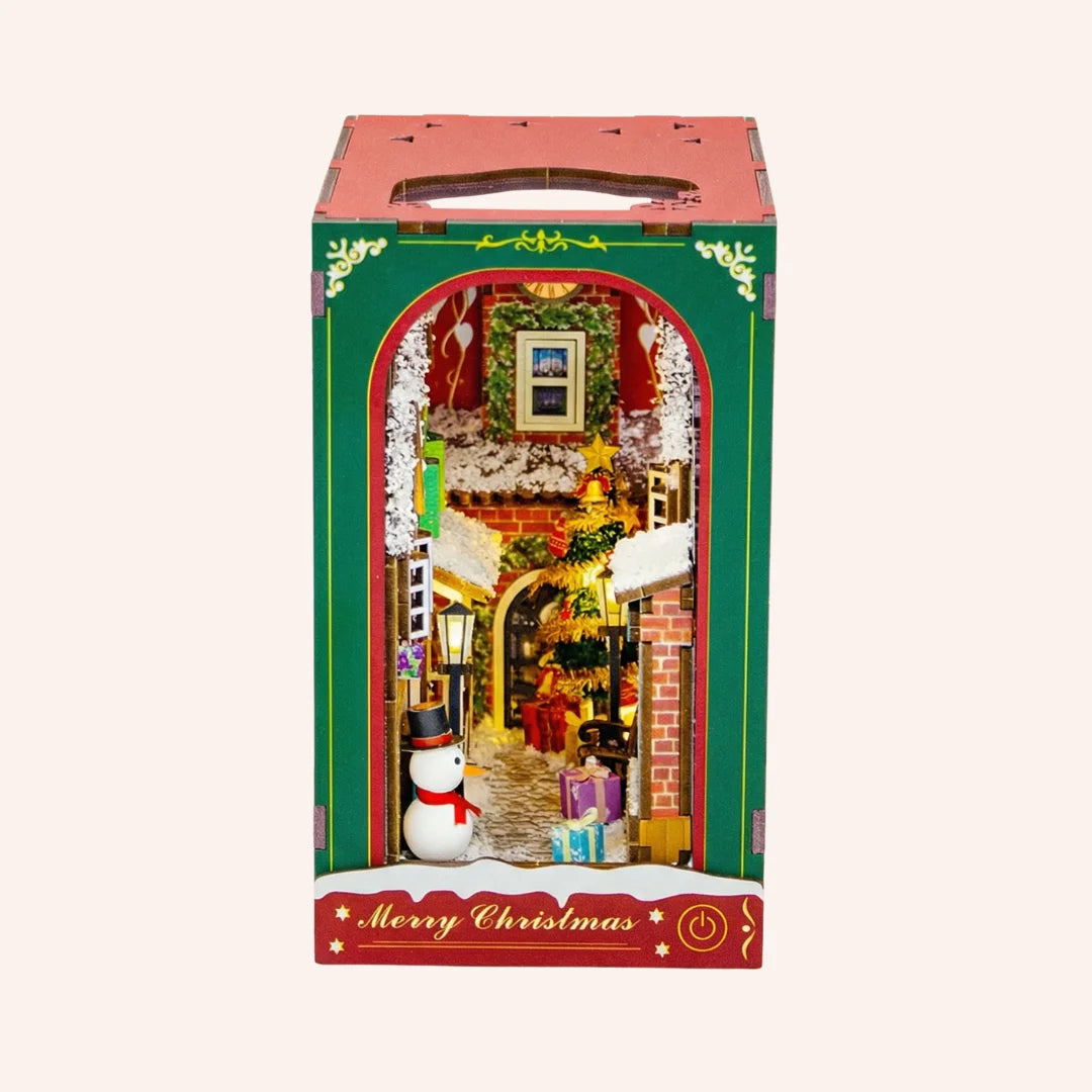 The Festive Alley miniature Christmas diorama kit with decorated shop front, snowman, and holiday scene inside box