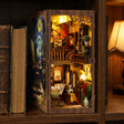The Artist's Studio book nook slotted on a bookshelf between books at dusk