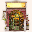 The Blossom House miniature red-brick florist book nook, lit, on a cream studio background