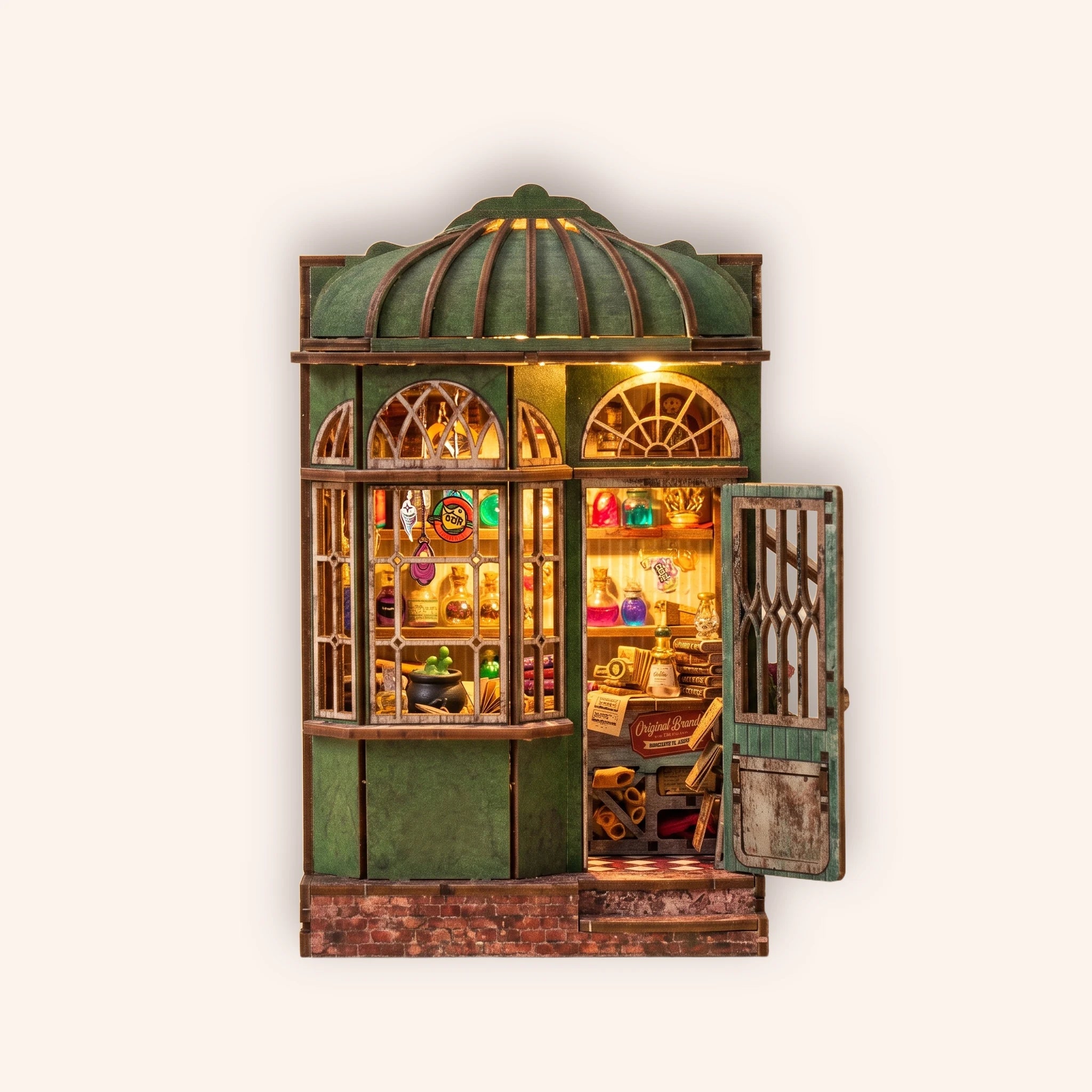 The Enchantment Shop DIY book nook kit, lit green wizard's magic shopfront on the TinyCraft cream background