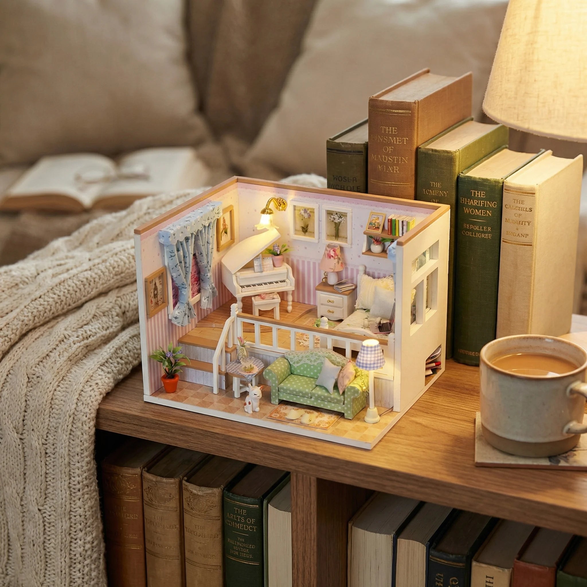 The Piano Parlour miniature dollhouse kit displayed on wooden side table with books and cozy blanket