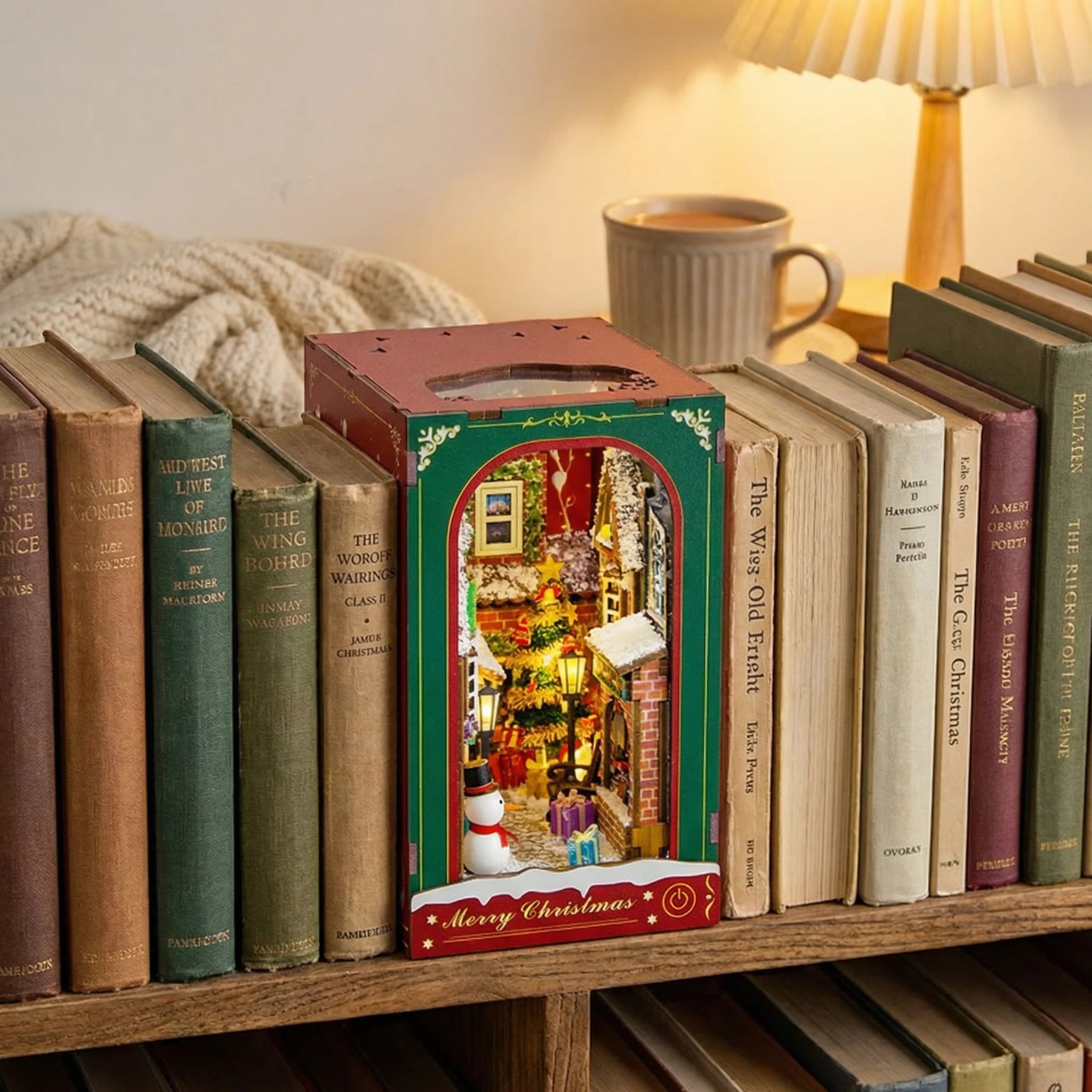 The Festive Alley miniature Christmas scene displayed on bookshelf with vintage books and cozy lamp
