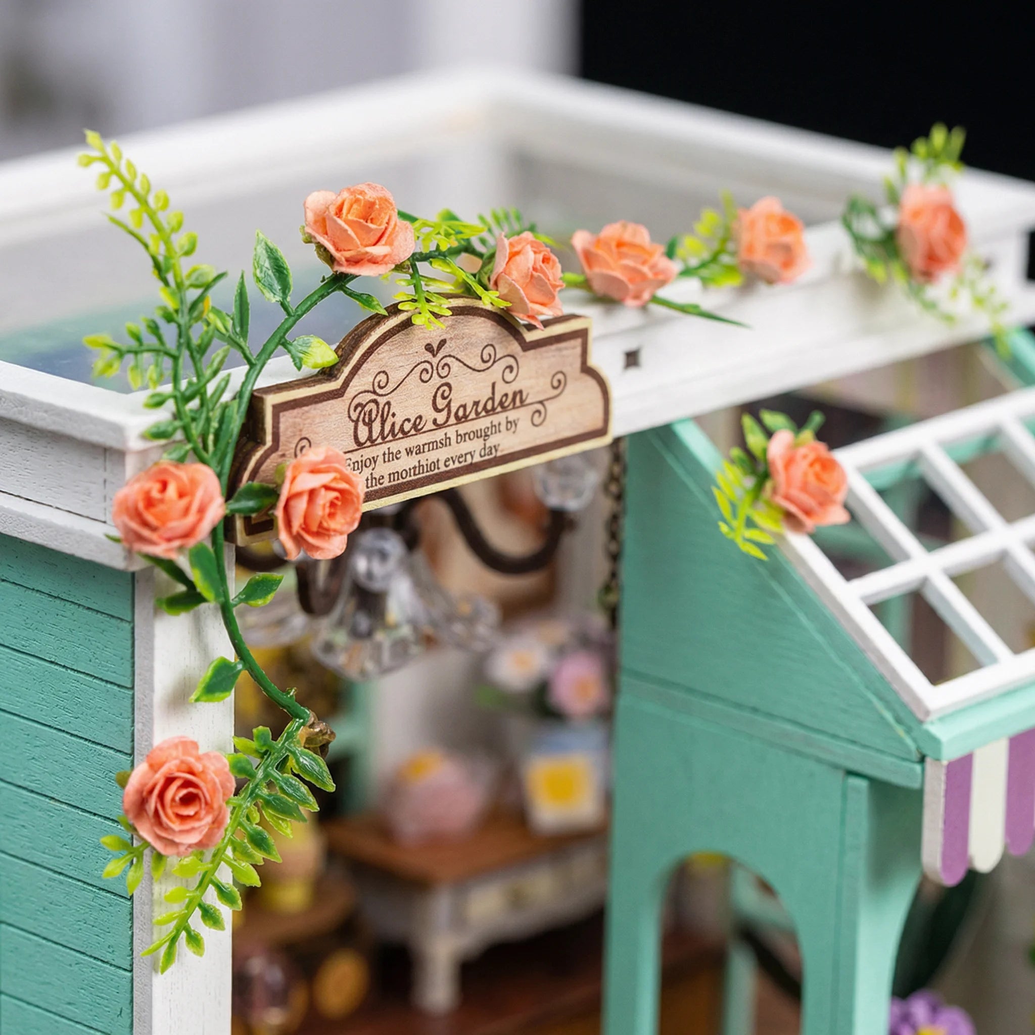 The Blossom Studio miniature dollhouse kit featuring detailed rose garden archway with coral flowers and wooden sign