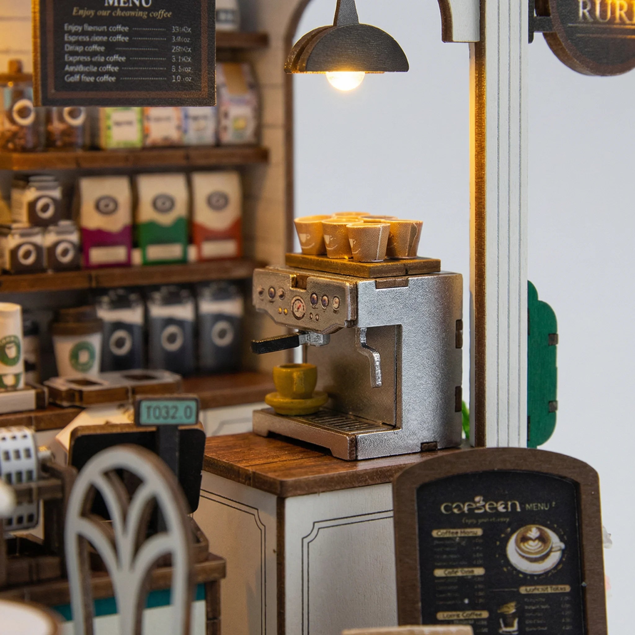 The Coffee Stop miniature kit espresso machine with cups under warming lamp and coffee menu boards on shelves