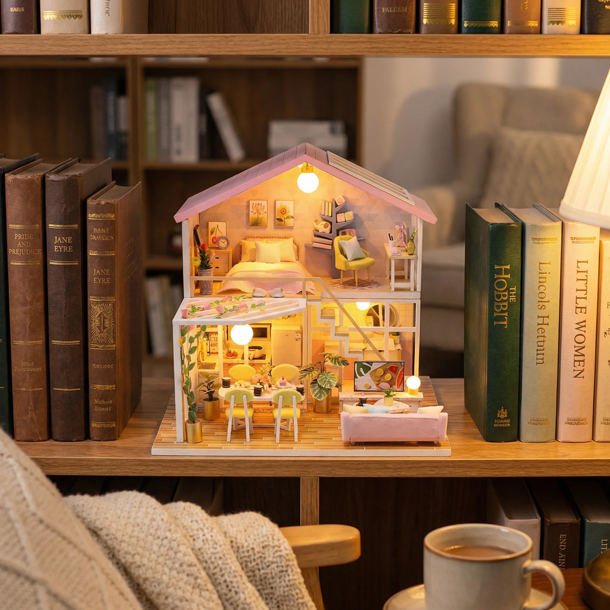 The Sweet Retreat miniature dollhouse kit displayed on bookshelf with tiny furniture and LED lights between classic books