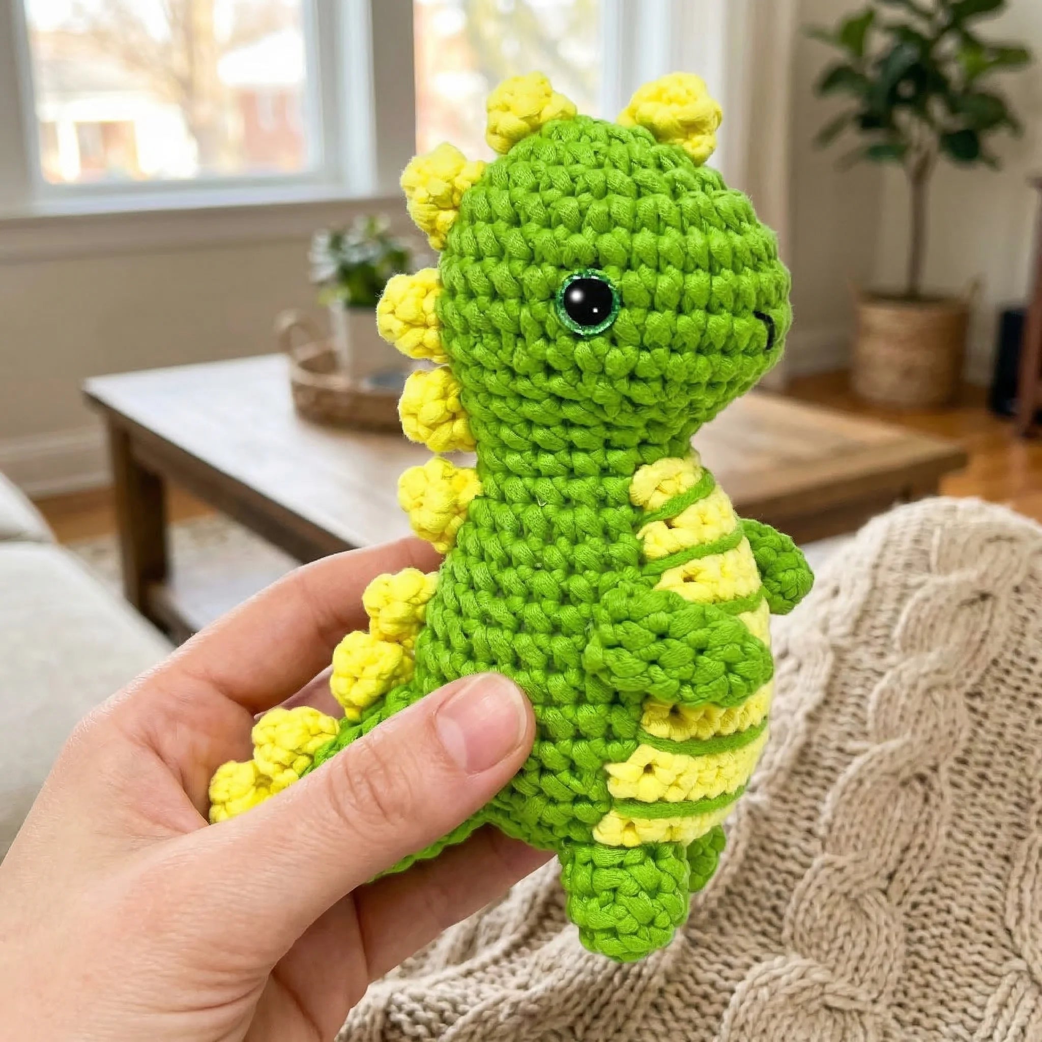 Bright green Rex the Dinosaur crochet amigurumi held in hand showing size and detail of finished mini plush toy
