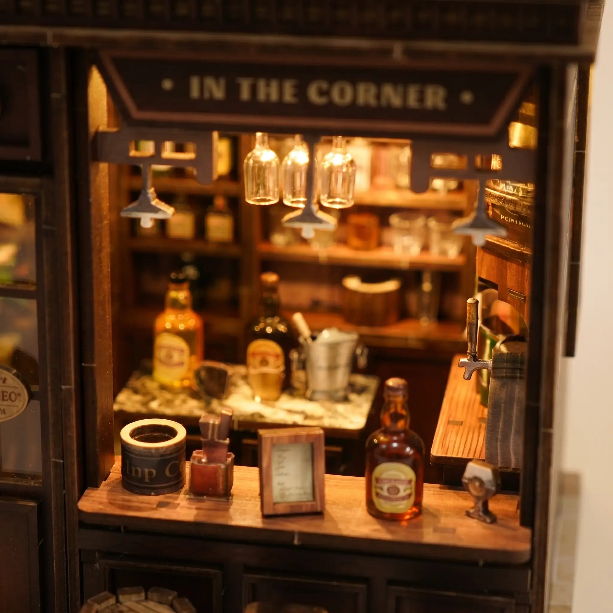 Close-up of the glowing bar counter lined with tiny bottles and glassware inside The Hidden Tavern