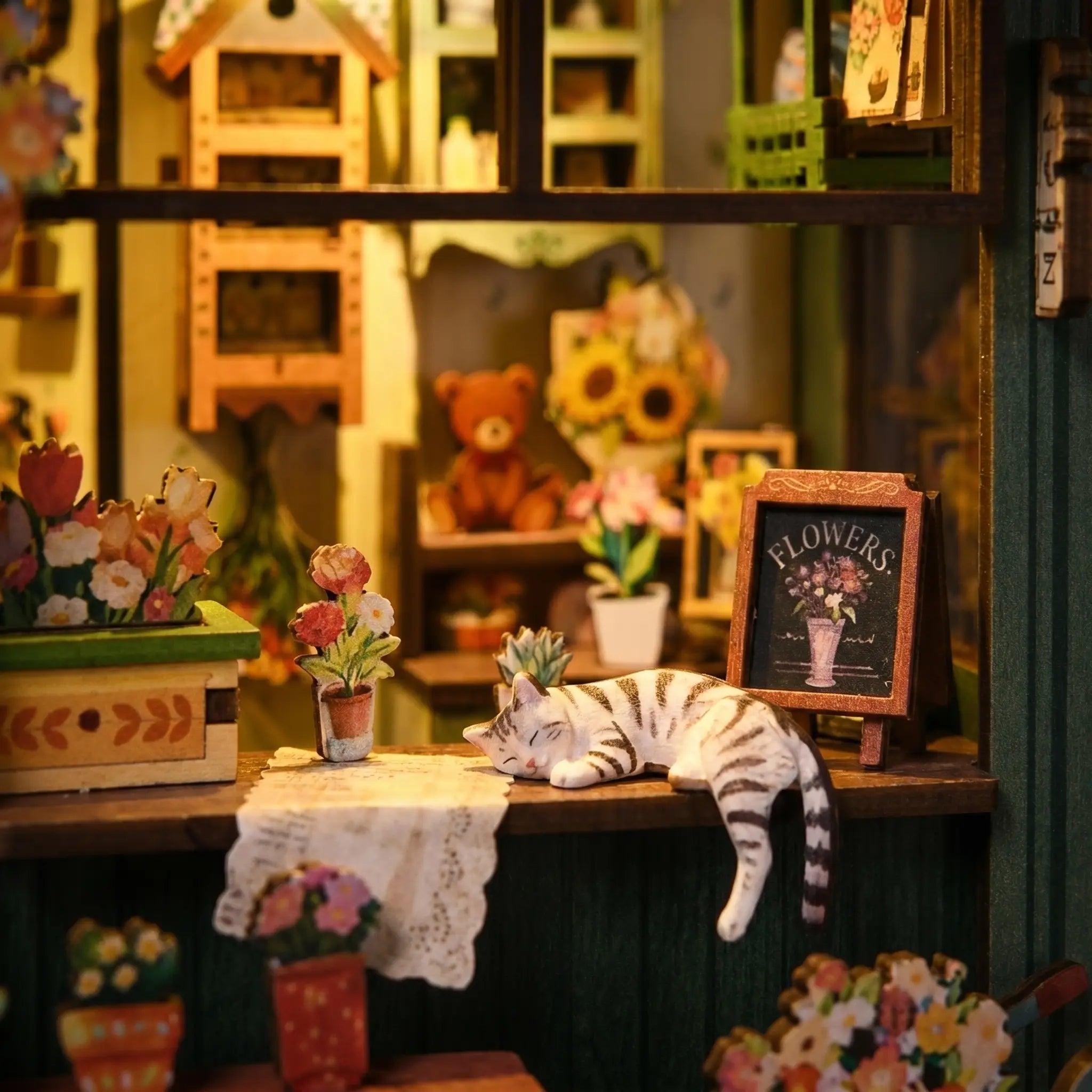 Close-up of the white cat asleep on the shop counter beside the chalkboard sign inside The Aura Verde Flower Room