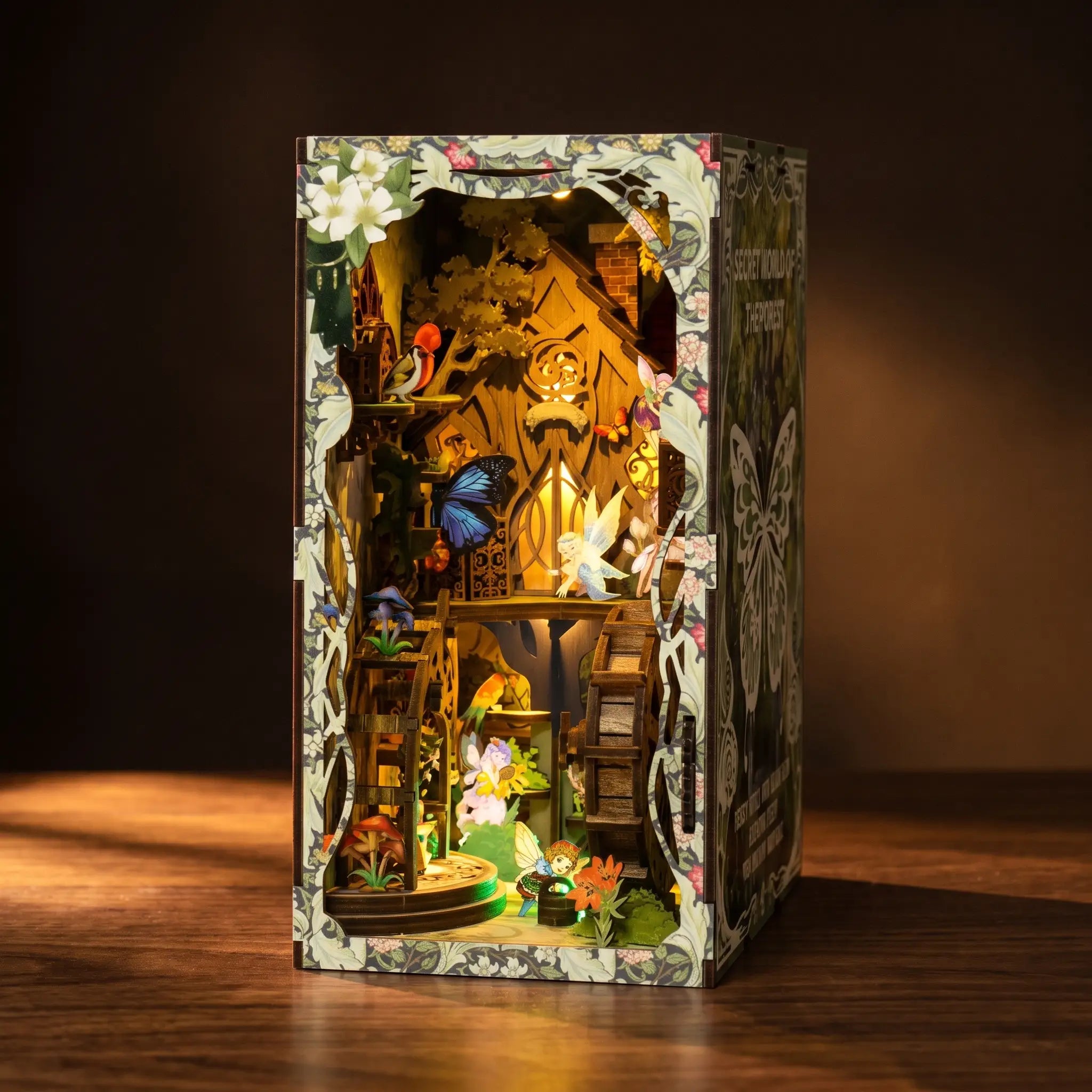 The Fairy Glen elf treehouse book nook glowing warm amber on a dark walnut surface