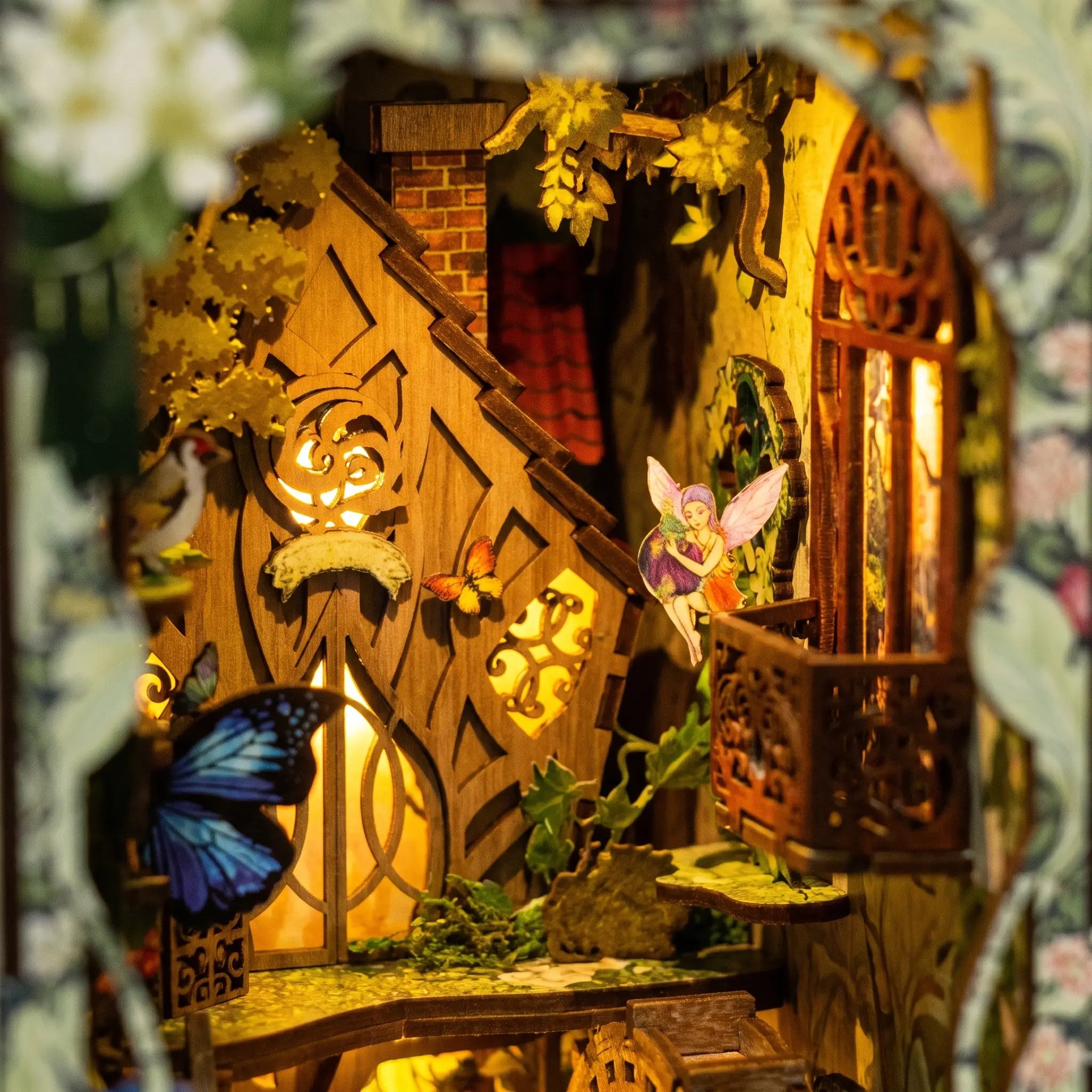 Close-up of the lit interior of The Fairy Glen, the tree-grown cottage and a winged fairy in warm lamplight