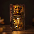The Book Café DIY book nook kit on a dark walnut surface, warm interior lights glowing