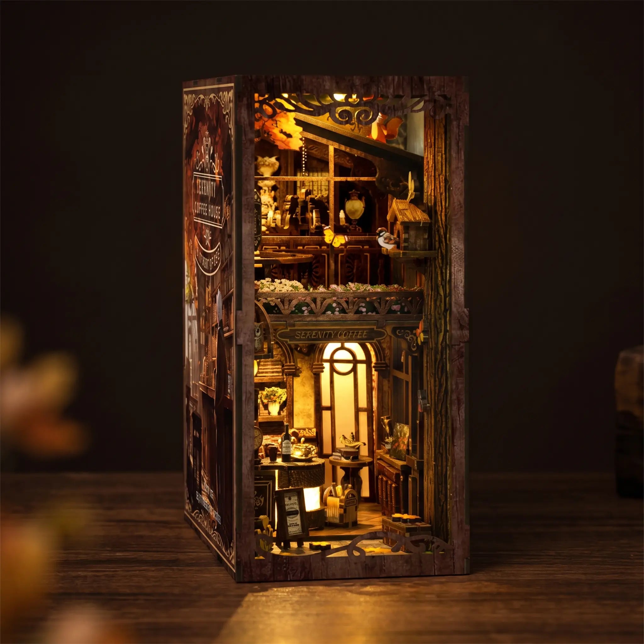 The Book Café DIY book nook kit on a dark walnut surface, warm interior lights glowing