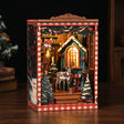 The Snow Cabin book nook on a dark walnut surface with the cabin window glowing warm
