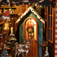 Close-up of the glowing arched cabin window with a wreath and the little reindeer
