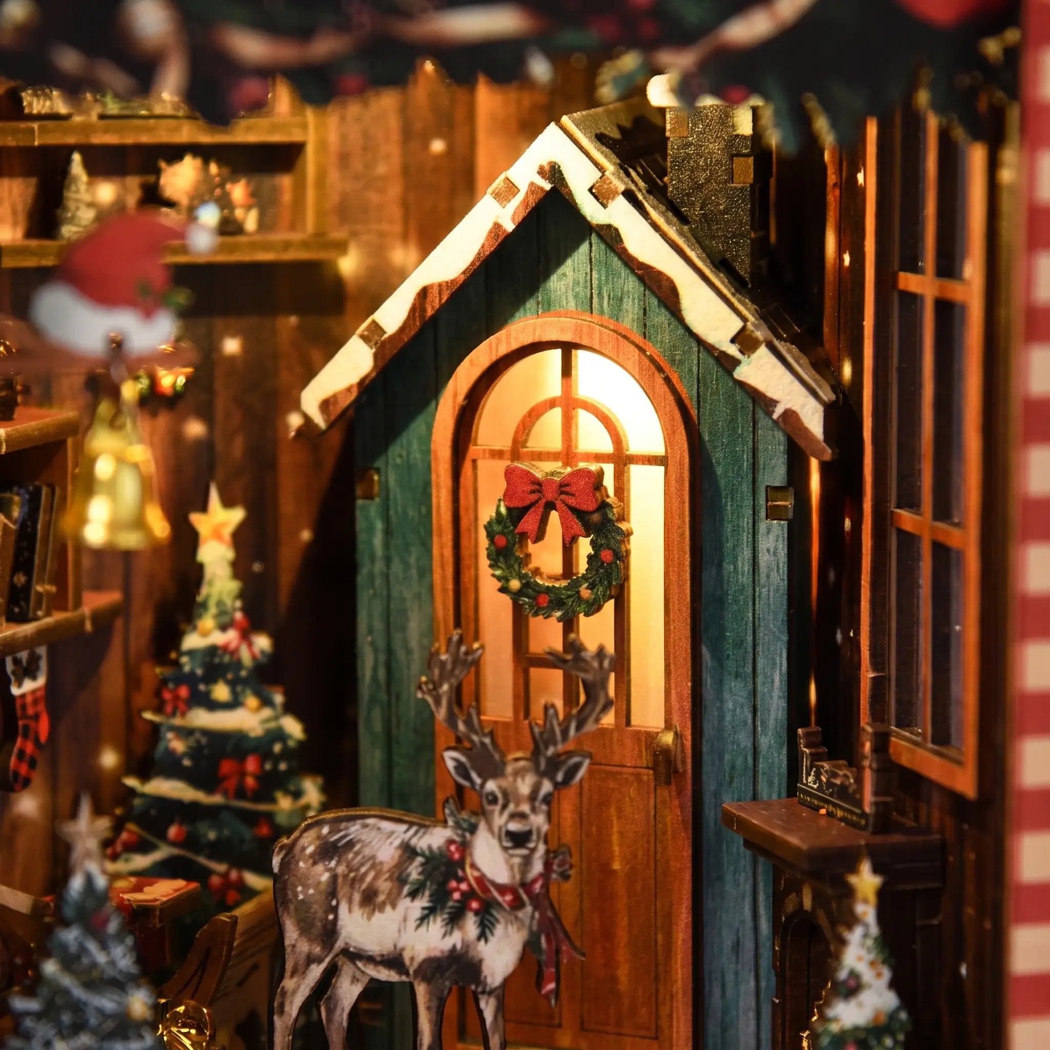 Close-up of the glowing arched cabin window with a wreath and the little reindeer