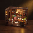 The Left Bank Study miniature roombox on a dark walnut backdrop with warm interior lighting