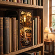 The Repair Shop book nook slotted on a shelf between books at dusk