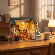 The Christmas Parlour on a wooden desk with a warm mug and books