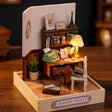 The Writer's Room miniature on a dark walnut backdrop, desk lamp glowing