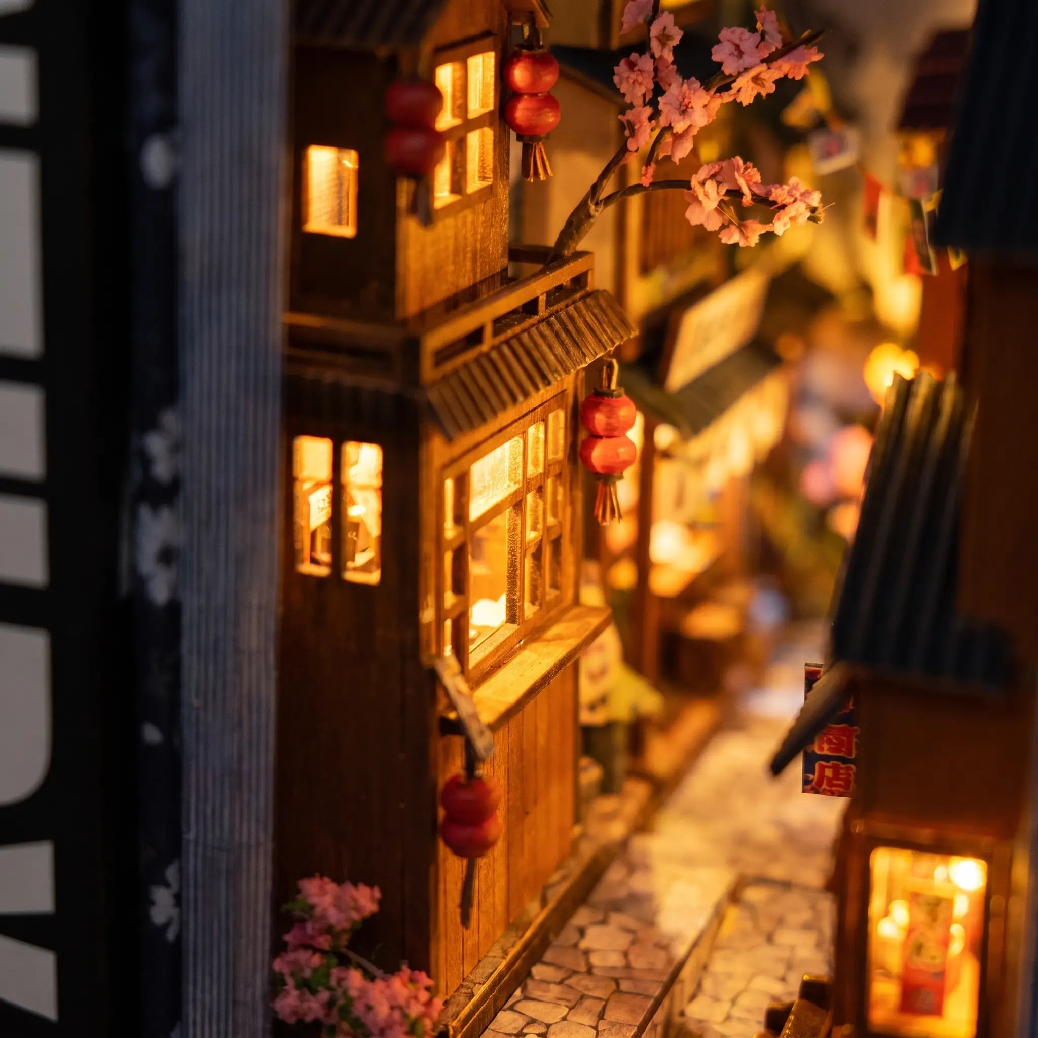 Macro close-up of a glowing lit shopfront and lanterns inside The Lantern Alley book nook