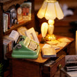 Close-up of the lit writing desk with the green typewriter and lamp