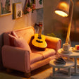 Close-up of the pink loveseat and acoustic guitar in The Sunday Lounge, warm amber glow