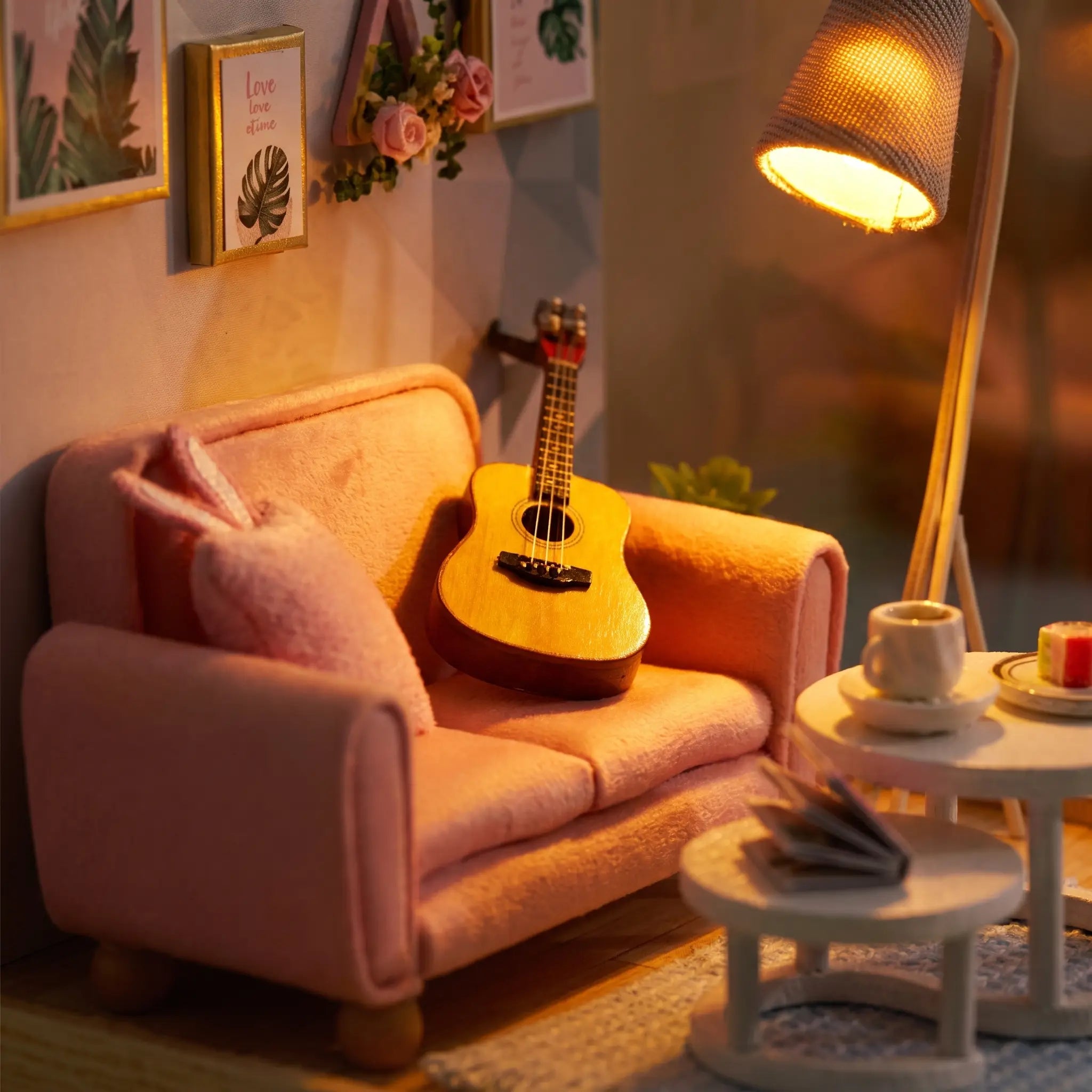 Close-up of the pink loveseat and acoustic guitar in The Sunday Lounge, warm amber glow