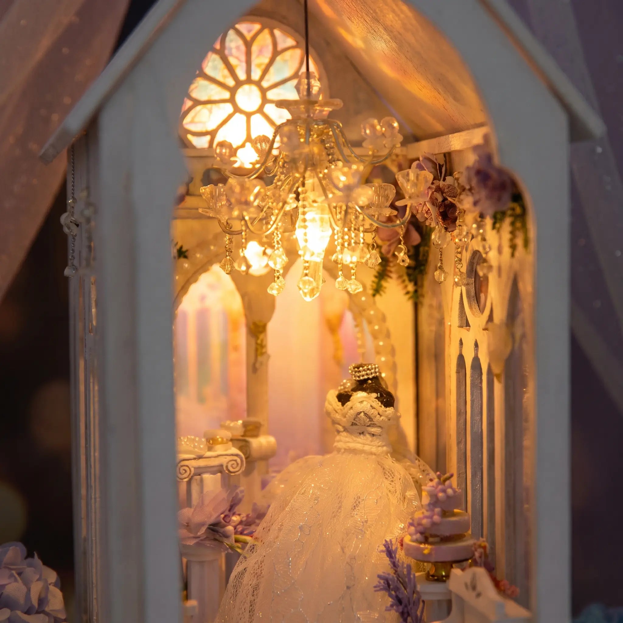 Close-up of the lit chapel interior, crystal chandelier, rose window and bride in white gown