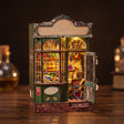 The Enchantment Shop DIY book nook kit, lit green wizard's magic shopfront on a dark backdrop