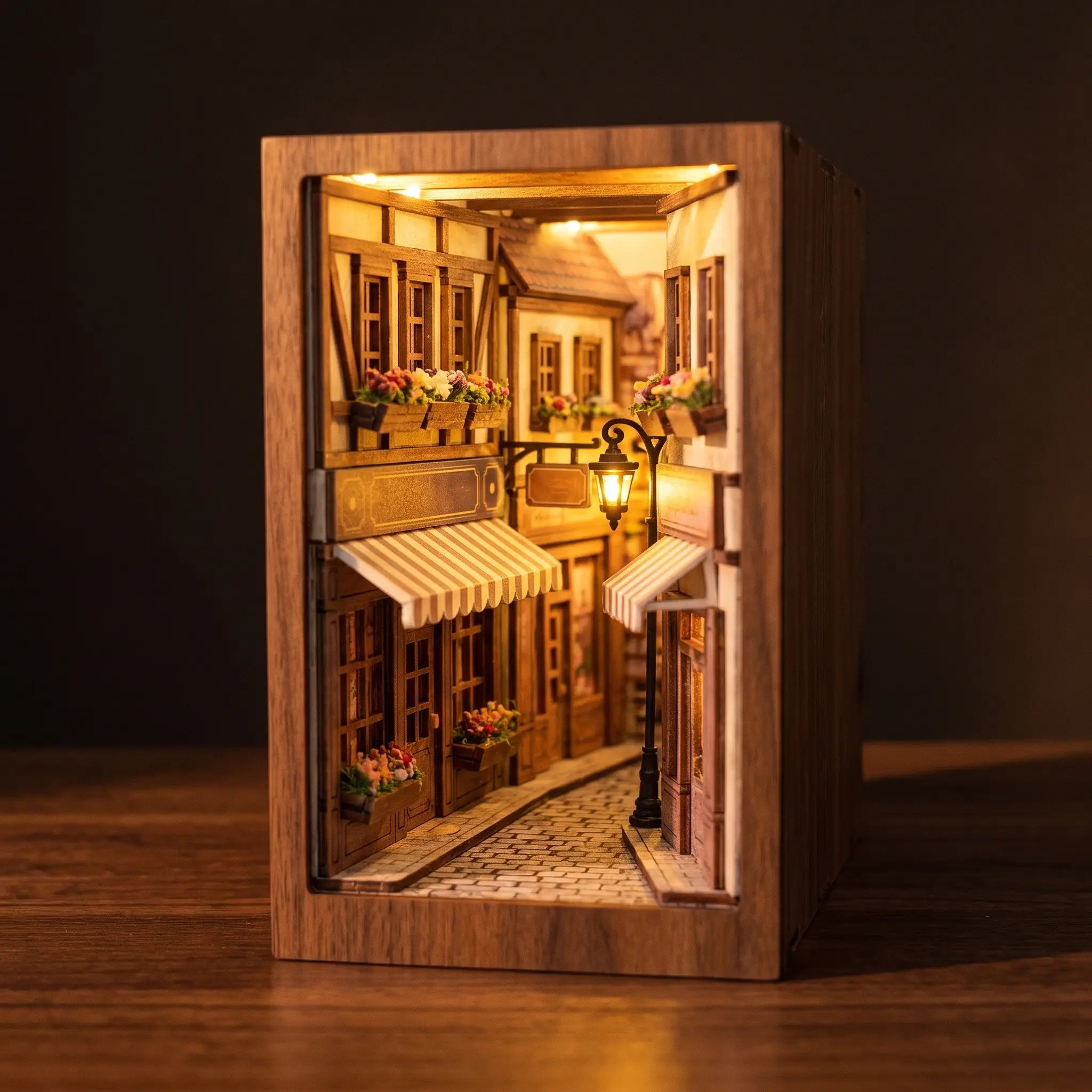 The Sunset Lane book nook on a dark walnut surface, warm interior glow