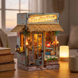 The Tiki Bar miniature on a wood desk beside books and a mug at dusk