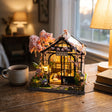 The Sakura Teahouse on a warm wood desk beside a mug of tea and books
