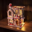 The Candy Cane Cottage miniature kit glowing on a dark walnut shelf at night