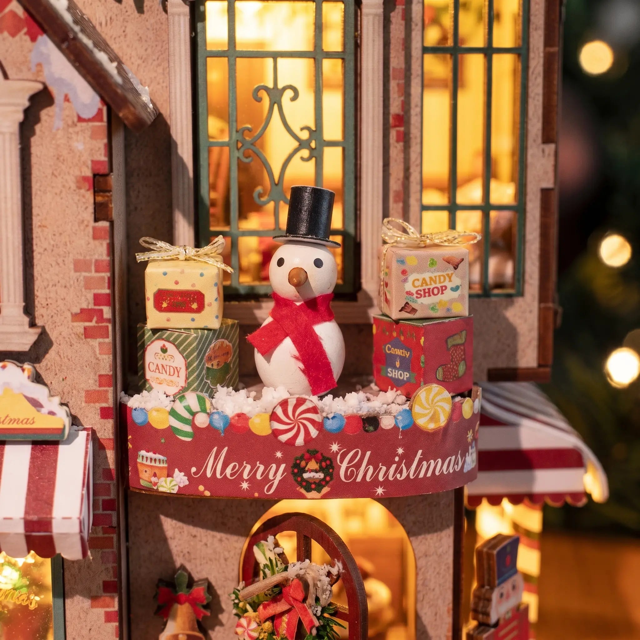 Snowman in a top hat among gift boxes on The Candy Cane Cottage ledge