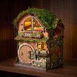 The Mossy Hollow book nook glowing on a dark walnut shelf at night