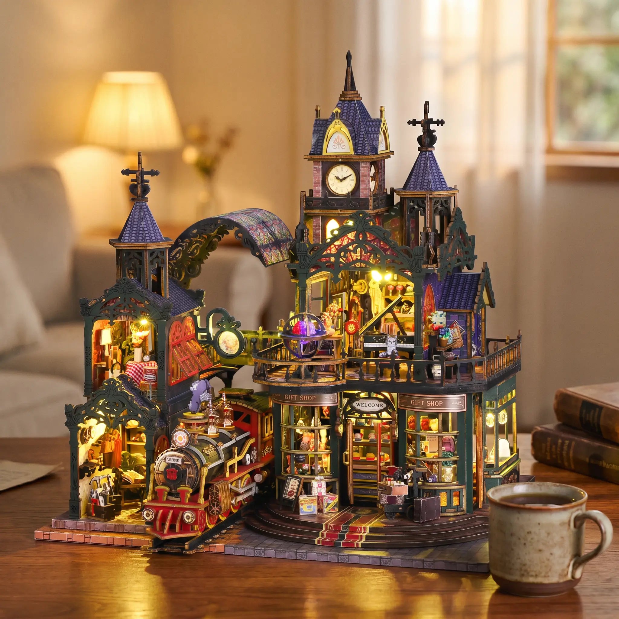The Clocktower Emporium lit up on a wooden desk at dusk beside tea and books