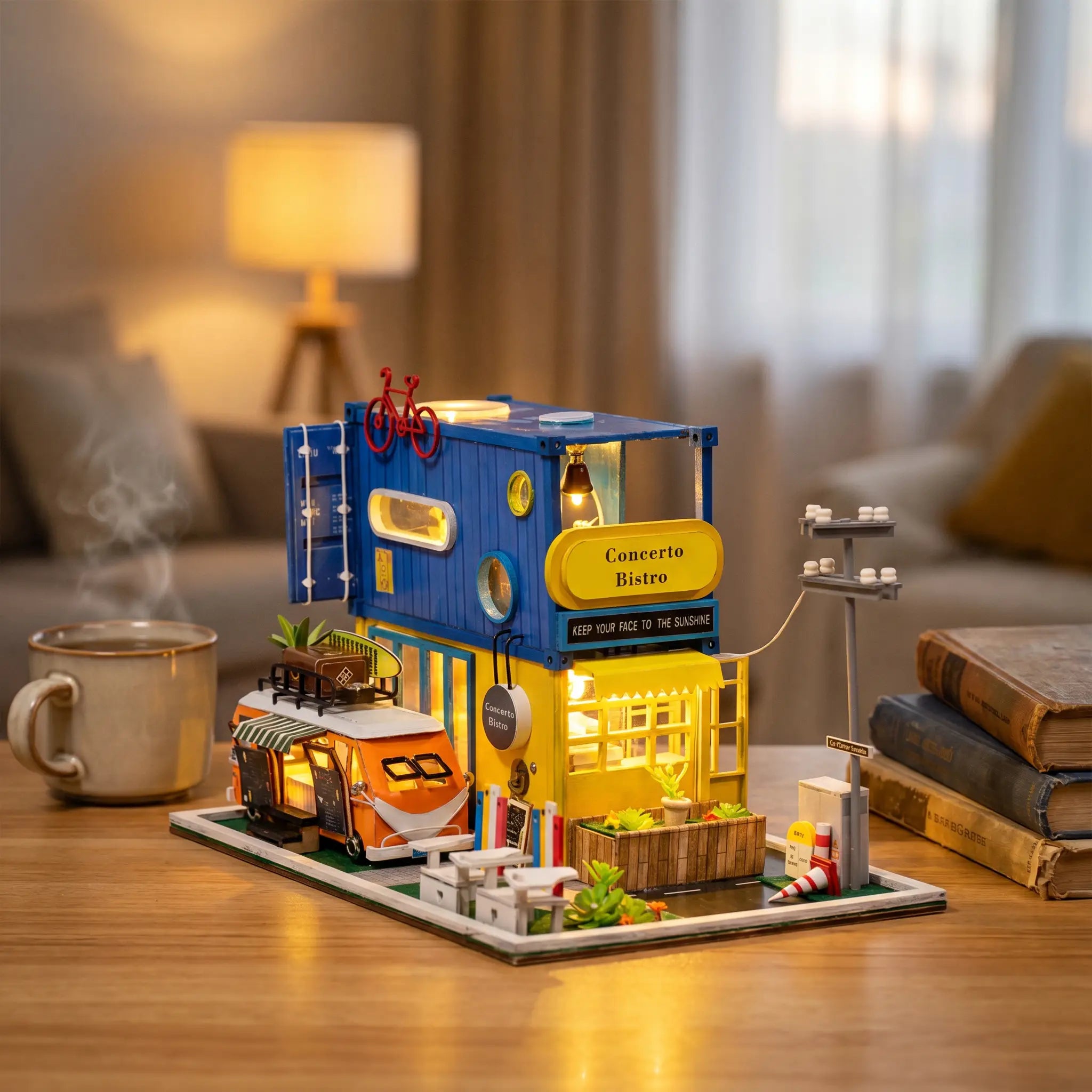 The Roadside Bistro miniature kit lit up on a wooden desk beside a mug of tea