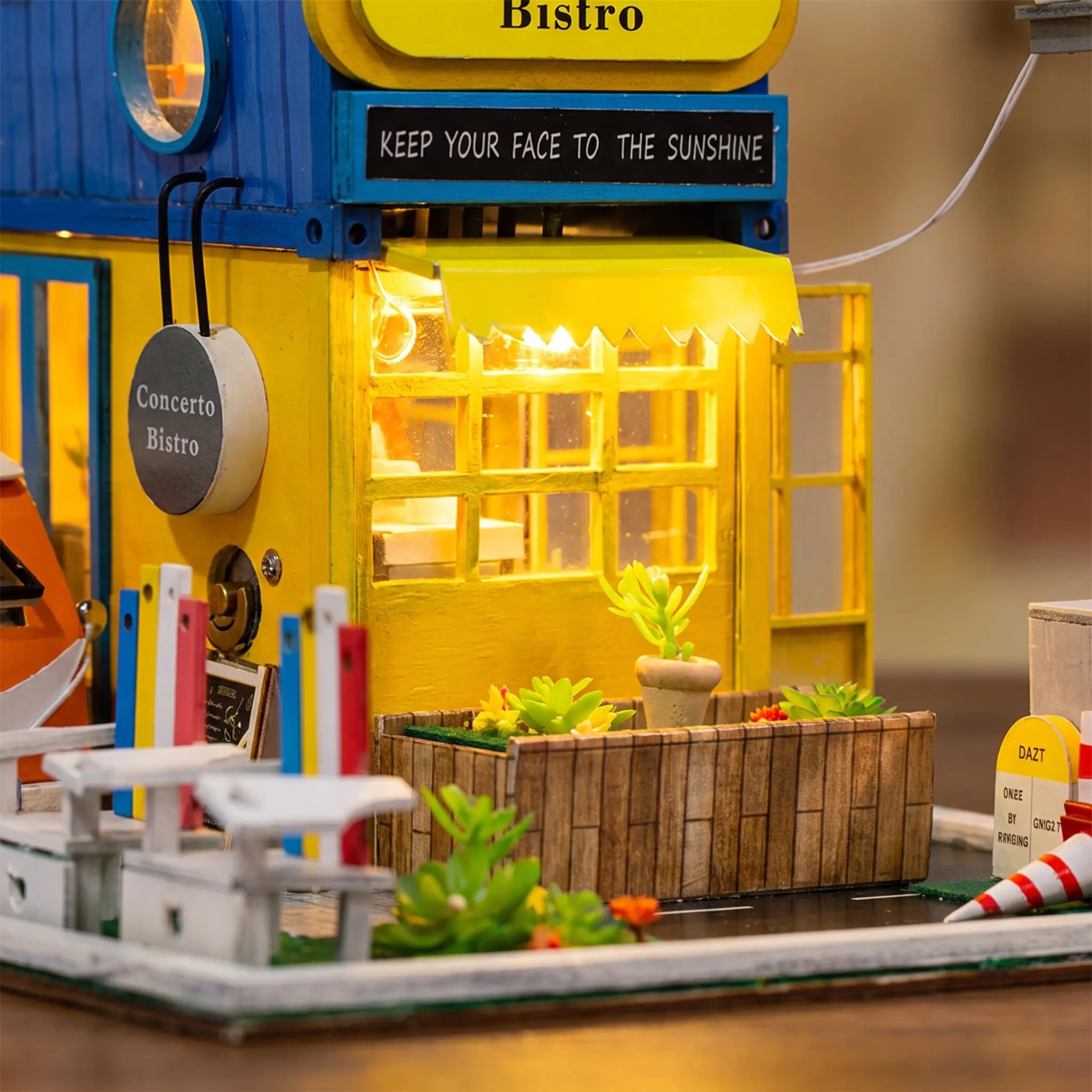 Close up of the glowing yellow cafe front with awning lights and succulent planter