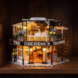 The Duchess's Tea Room miniature kit glowing on a dark walnut shelf at night