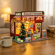 The Sugarplum Shop glowing on a desk at dusk beside a mug of tea