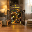 The Moonlit Brew book nook on a warm wooden desk at dusk